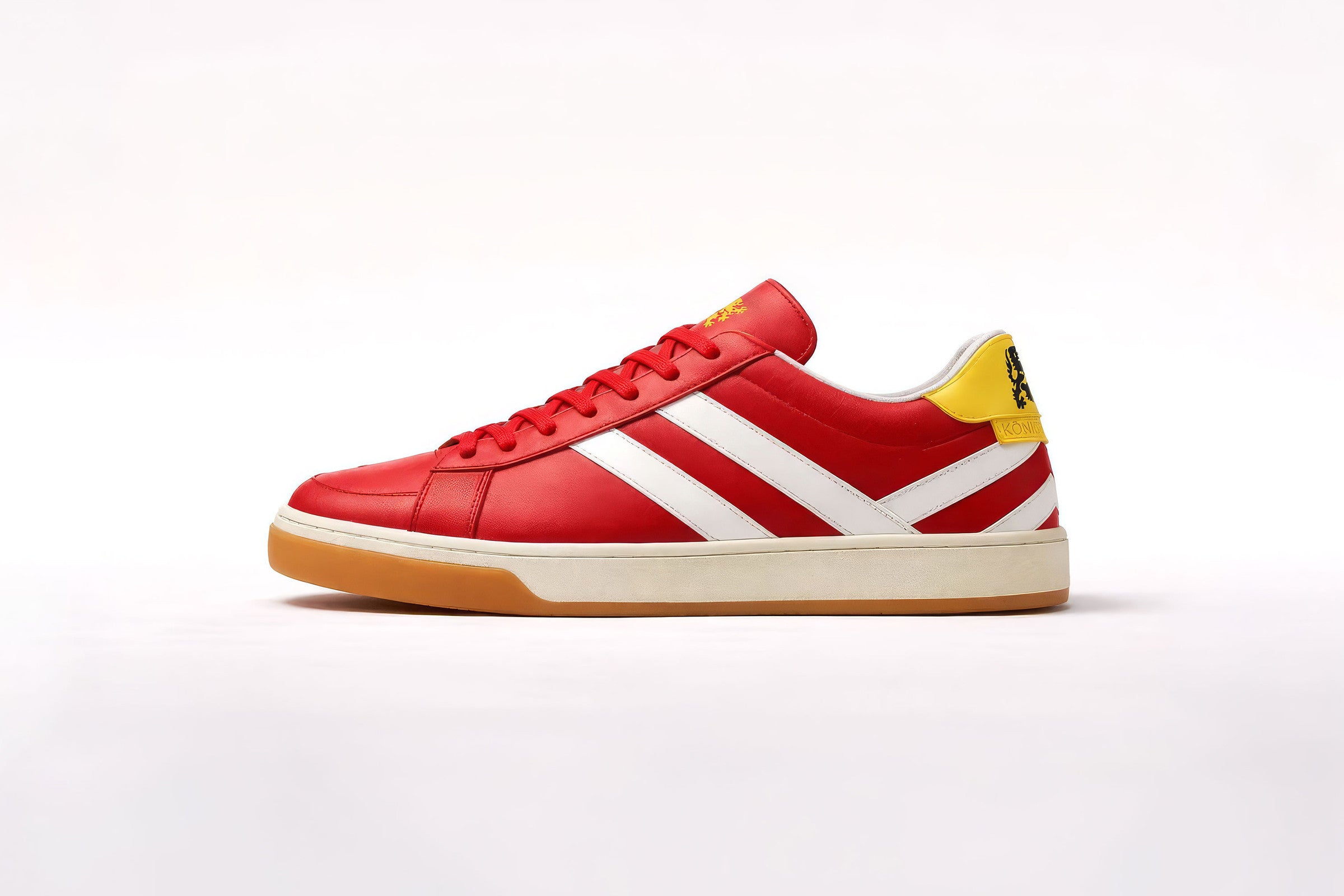 K///STRIPE Sneaker in der Seitenansicht: rotes Glattleder, weiße gespiegelte Streifen, gelber Fersenbesatz mit Königsteiner Löwe, zweifarbige Gummisohle.